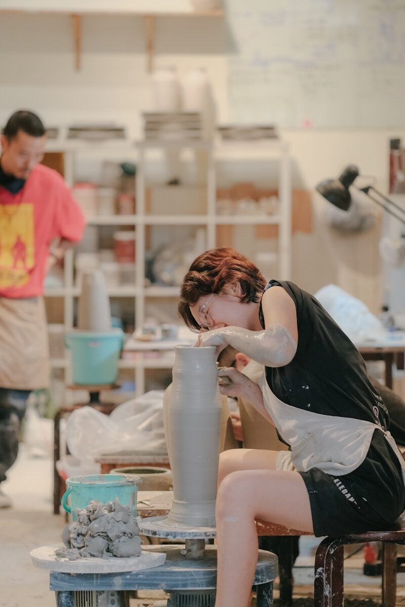 a woman is making a vase out of clay